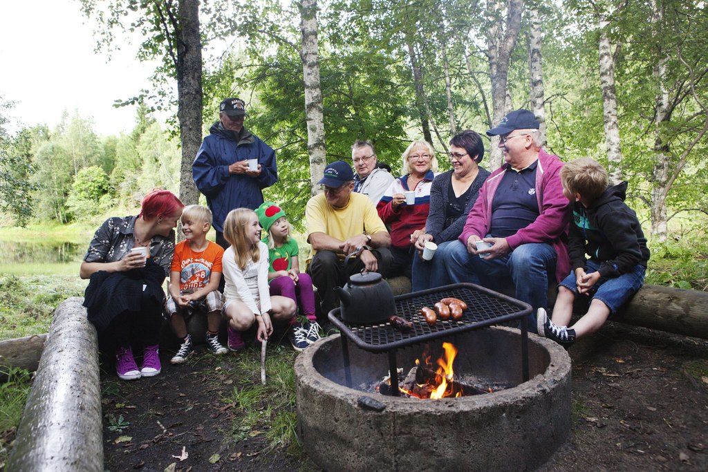 Kuvituskuva. Ihmisiä paistamassa makkaraa nuotiolla.